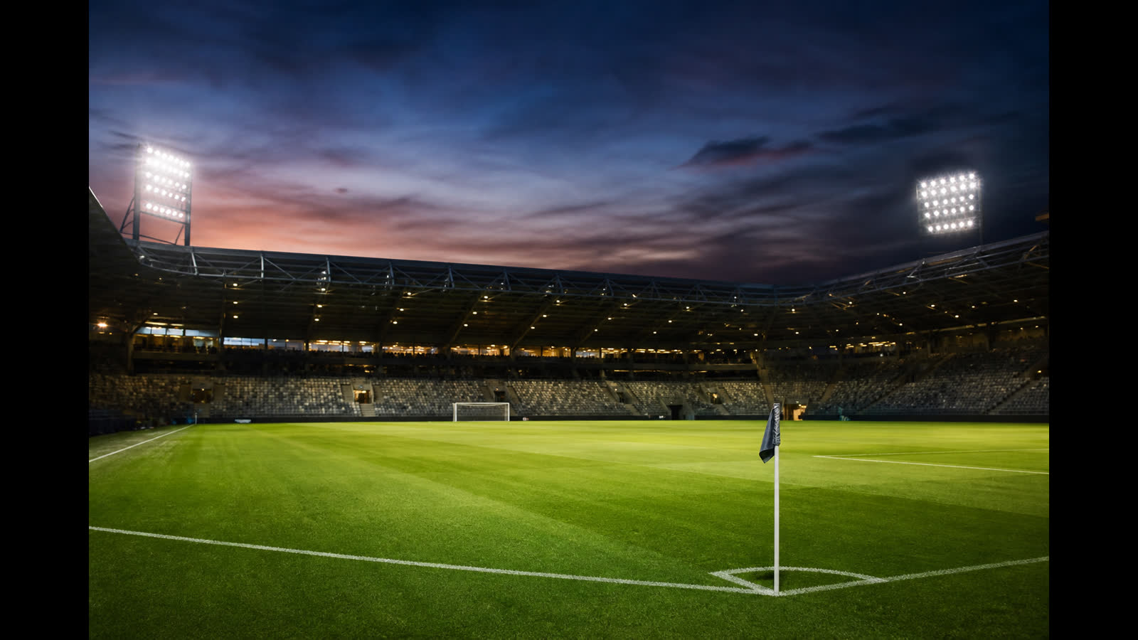 Tom fotbollsarena i skymning med belyst plan och tomma läktare — atmosfär inför europaspel