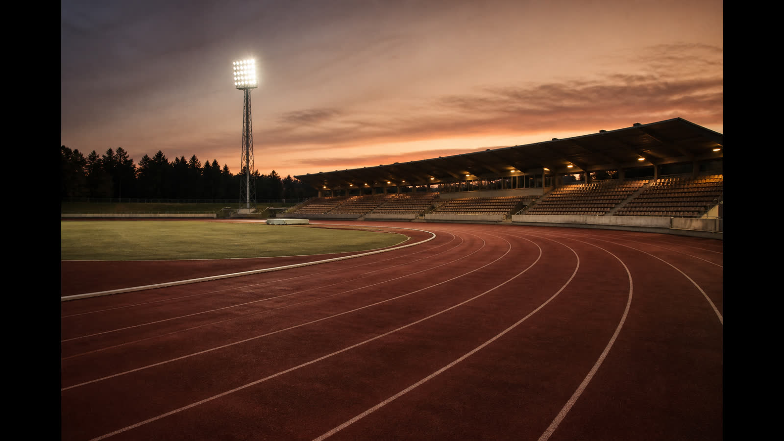 Tom friidrottsarena i skymning med röd löparbana och läktare — illustration till Finnkampen 2026 resultat
